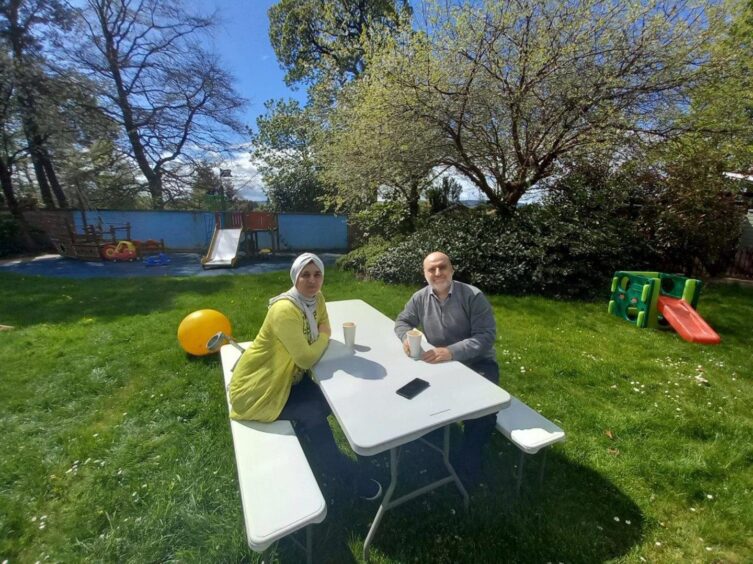 Qusai and Esraa Al-Hamdan at an outdoors table in a summer garden