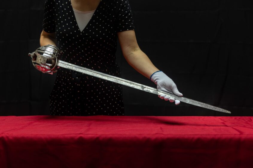 A person holds Bonnie Prince Charlie's sword.