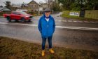 Alasdair Gow standing next to traffic on the Auchterarder-Aberuthven road with the Shinafoot junction behind him.