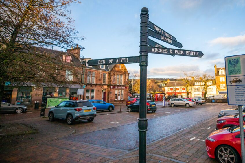 Market Square, Alyth, with cars parked and a signpost leading to a number of local attractions