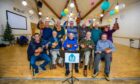 Members of the Auhterarder and District Men's Shed group holding up their ukuleles for the camera.