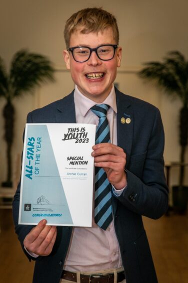 Archie Curran holding his certificate and smiling