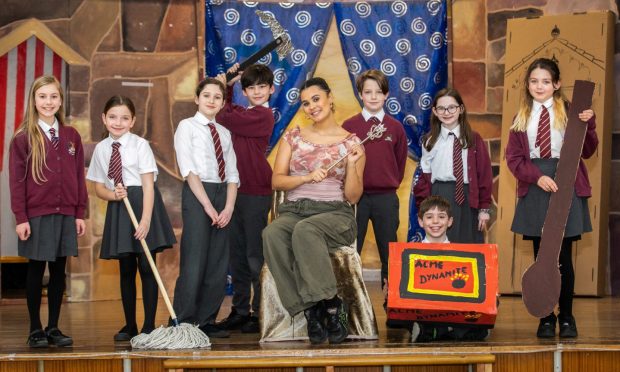 Image shows: actor Tinashe Warikandwa and some primary 6 and 7 pupils at Greyfriars Primary School. Tinashe is back at her former school for a visit and to talk to the children about playing Cinderella in the year's Byre Theatre pantomime. She is sitting on the stage surrounded by the children.