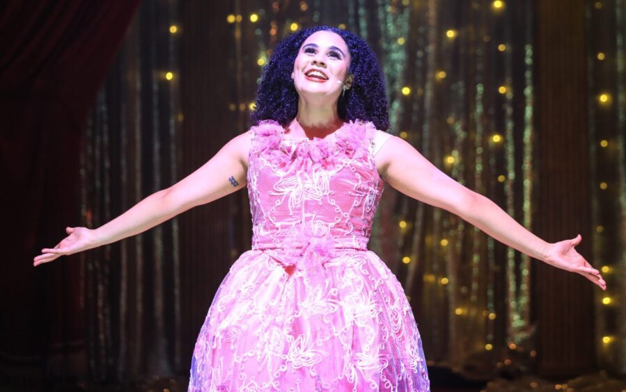 Image shows Tinashe Warikandwa as Cinderella at The Byre Theatre. Tinashe is wearing a pink dress and singing her heart out.