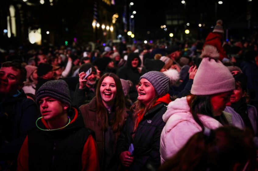 Crowd shot with focus on two smiling young women in winter coats and hats during the 20223 Perth Christmas lights event