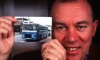 Sir Brian with a picture of the first bus operated by Stagecoach. Image: DC Thomson