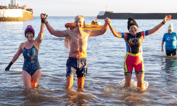 Friends celebrate as they take part in the annual New Year Dook at Arbroath. Image: Paul Reid