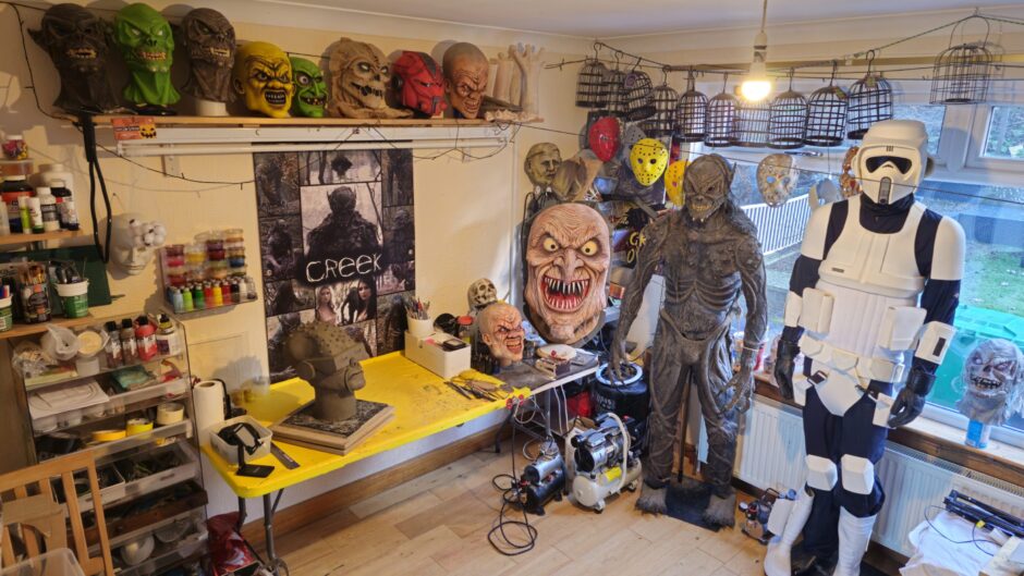 Image shows Keith Robson's home workshop with some of the weird and wonderful masks and creature costumes he has handmade.