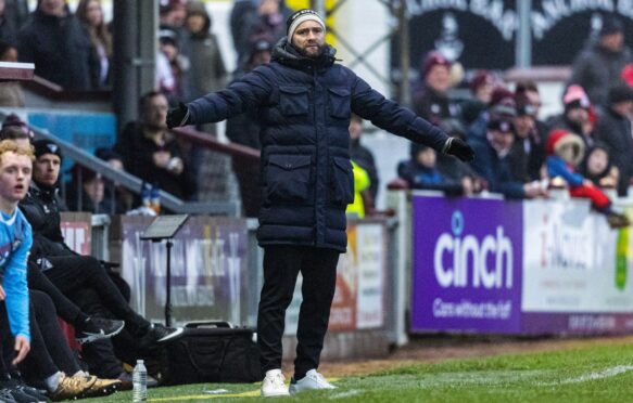 Dunfermline Athletic F.C. manager James McPake stretches out his arms on the sidelines during a game.