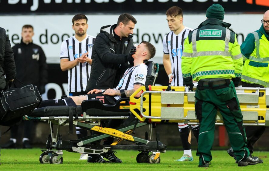 Dunfermline Athletic F.C. defender Sam Fisher leaves the pitch on a stretcher surrounded by medical staff after sustaining head and facial injuries against Raith Rovers.