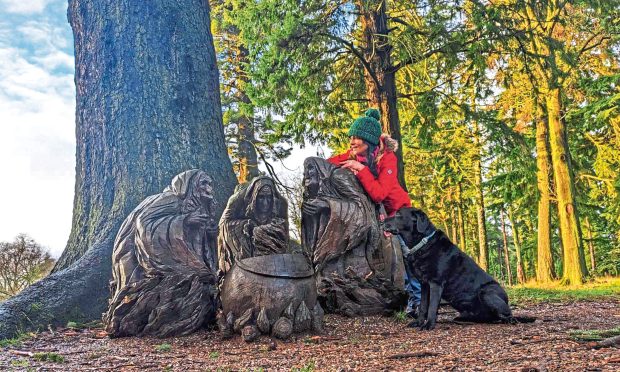 Gayle Ritchie and her dog Toby check out the sculpture of the three witches on the Macbeth Trail at Glamis Castle. Image: Gayle Ritchie.