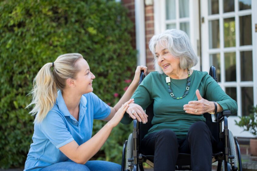 A care worker with an elderly woman in a wheelchair.