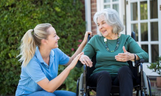 A care worker with an elderly woman in a wheelchair.