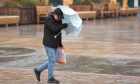 Person battles the wind and rain during Storm Babet at City Square, Dundee on 19th October 2023.