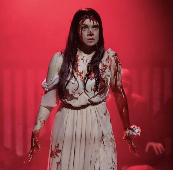 Lucy Duffy covered in fake blood on stage as the lead role in Carrie.