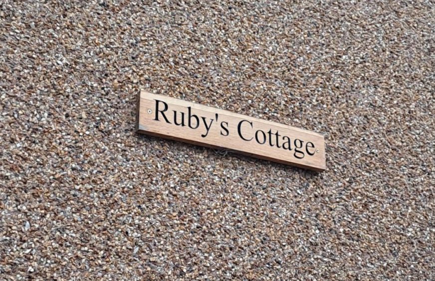 Ruby's Cottage wooden sign on wall of property in Crieff