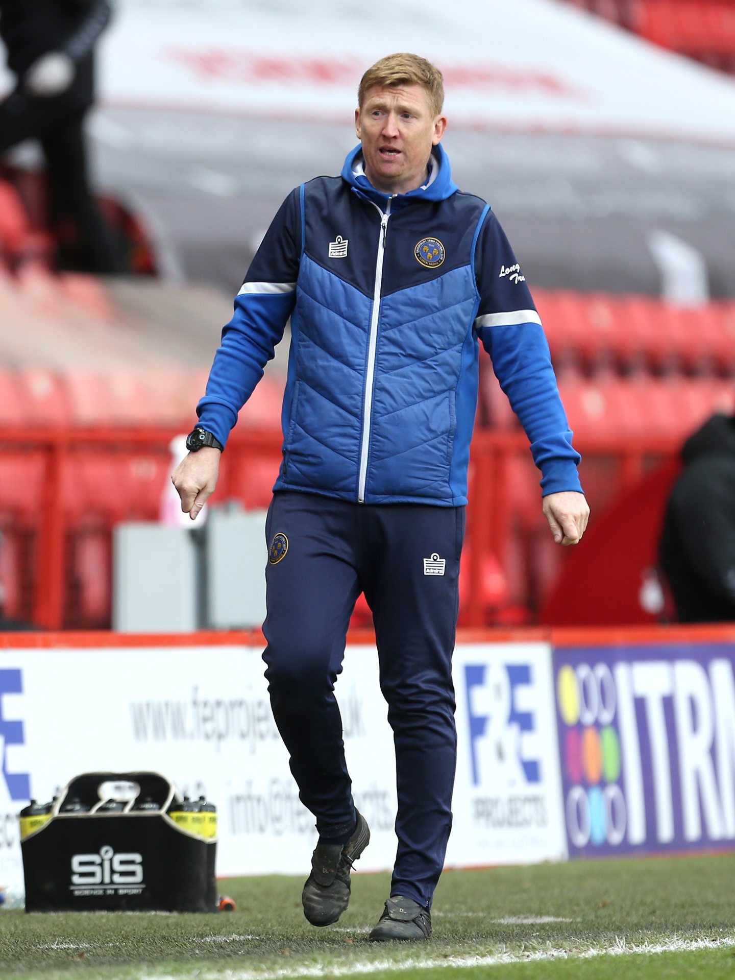 David Longwell in a tracksuit and bench jacket on the sidelines
