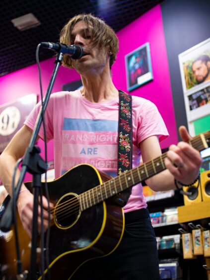 Nick Shane plays in an HMV store while wearing a T-shirt which says: 'Trans rights are human rights'.