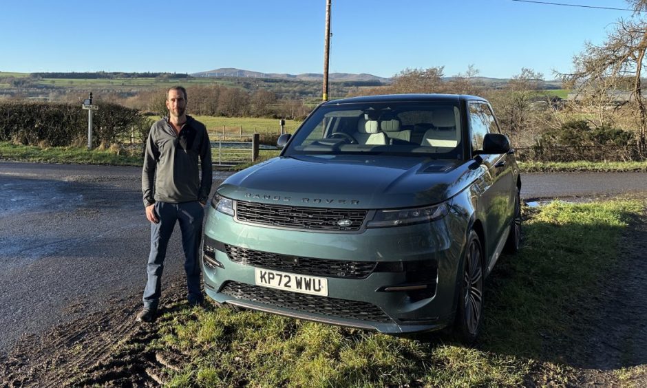 jack McKeown stands beside the new Range Rover Sport, which is parked beside a country road with fields in the background