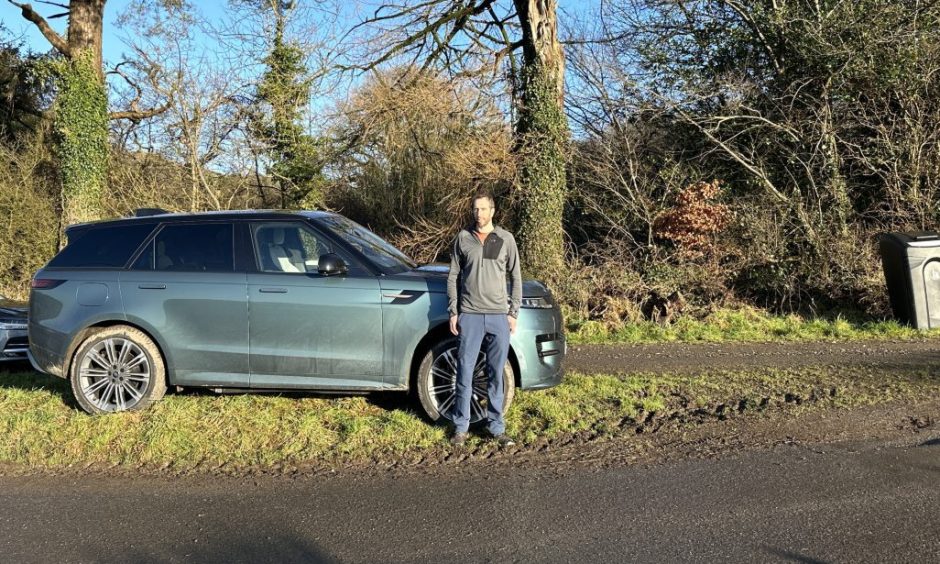 Jack McKeown beside the new Range Rover Sport PHEV, which is green and seen from the side on