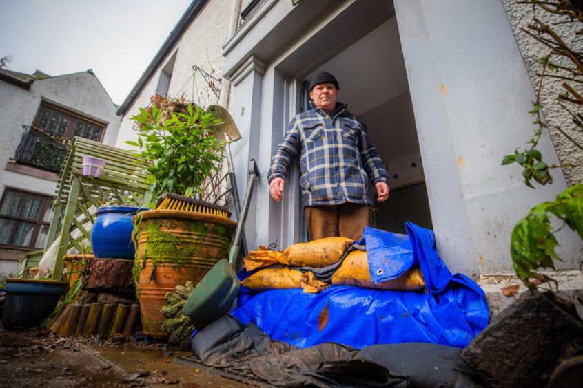 Niall McNab standing in front of a pile of dirty sandbags outside his Dunkeld home.