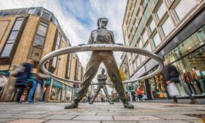 View of Perth High Street with well known 'leaning men' statue in foreground