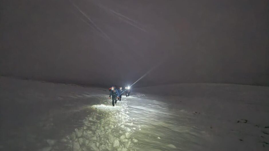 Tayside Mountain Rescue Team members trudging through snow by torchlight