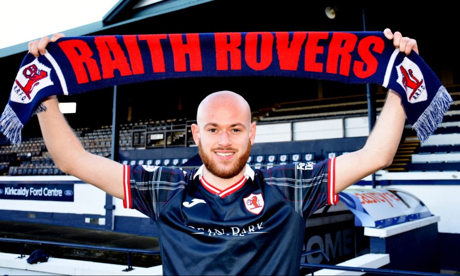 Zak Rudden holds a scarf above his head as he signs on loan for Raith Rovers.