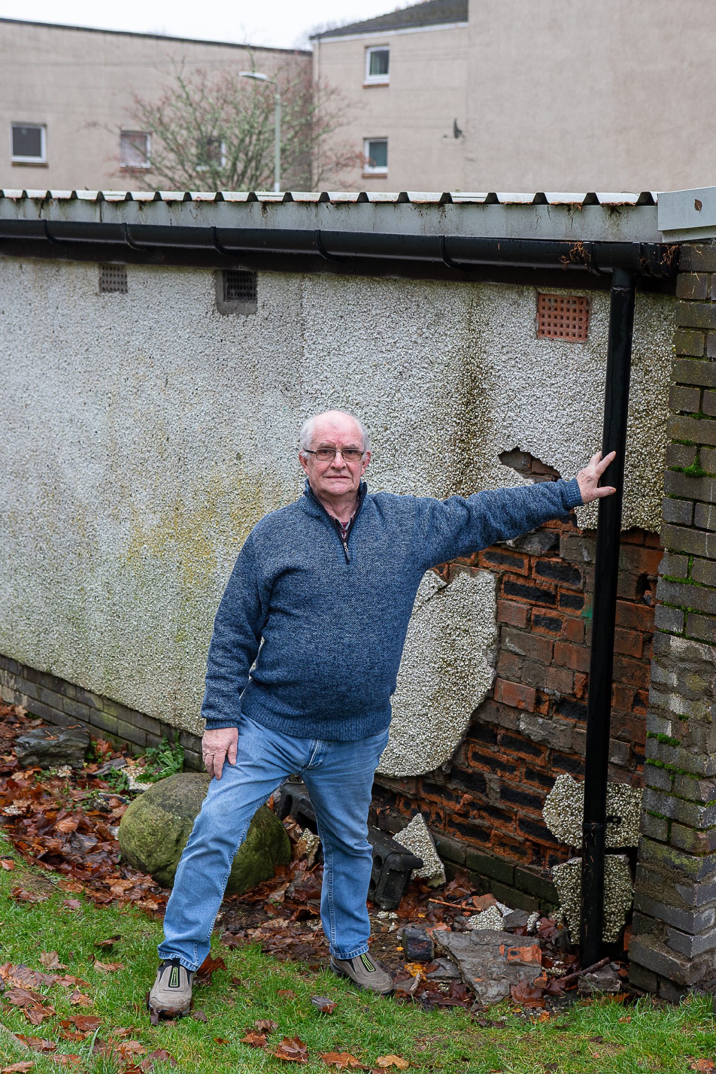 Norman Hawkes standing next to a wall with exposed brickwork in Kennedy Place, Pitlochry