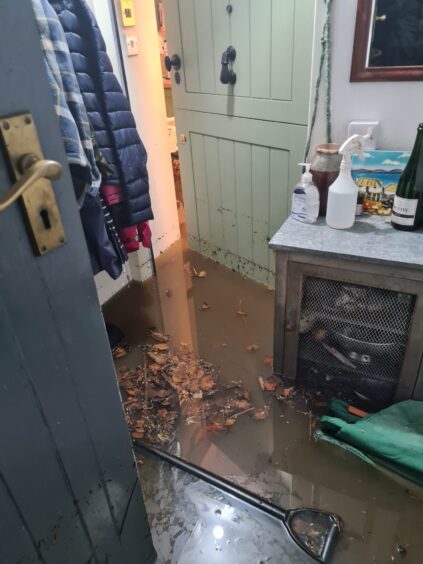 door leading to Niall McNab's home showing deep dirty floodwater with leaves and tools floating in it