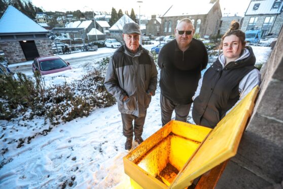 Academy Court residents with one of the empty grit bins. Image: Mhairi Edwards/DC Thomson