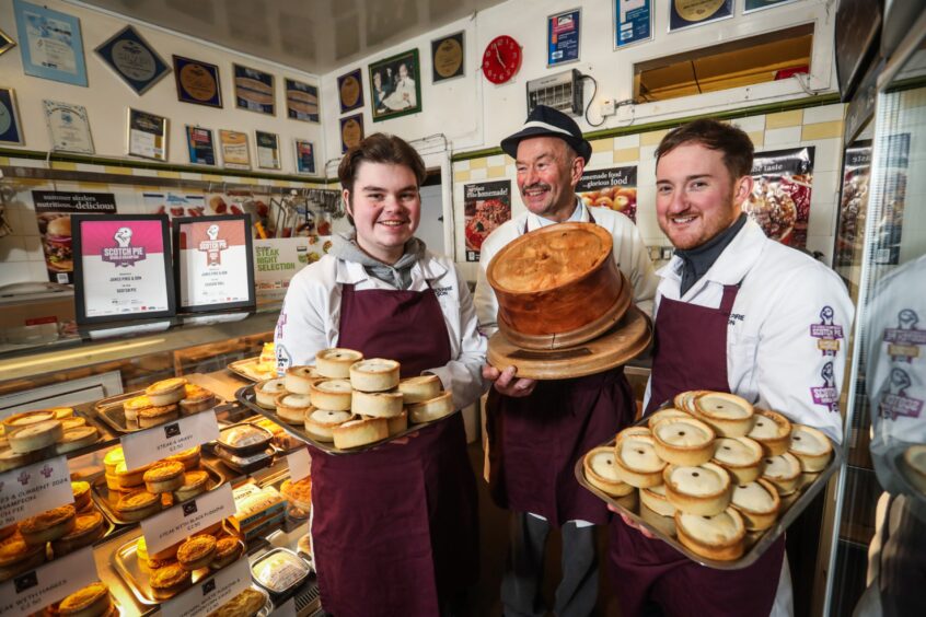 Assistant Lewis Hackney, owner Alan Pirie and manager James Small in the Newtyle shop. Lewis and James are holding trays of pies and Alan is holding a trophy in the shape of an enormous pie