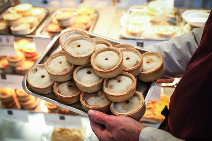 hand holding a tray of Scotch pies