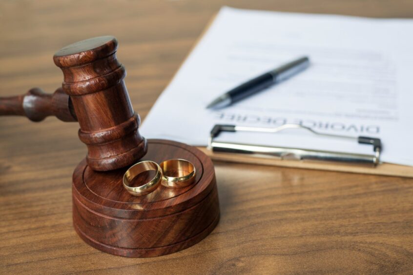 Judge's gavel with wedding rings and divorce papers