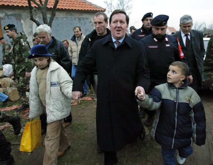 George Robertson in Kosovo in 2003 holding hands of children