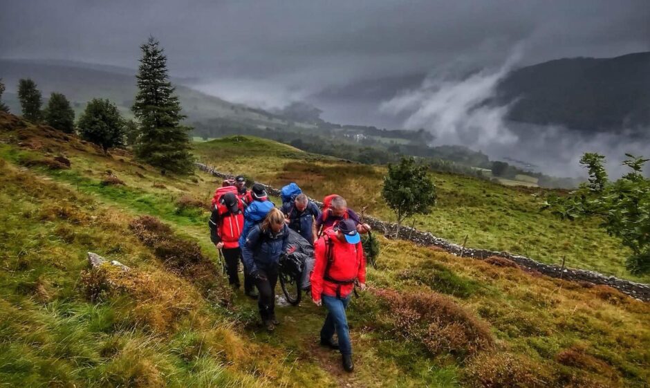 Tayside Mountain Rescue Team members carrying a casualty on a stretcher across moorland near Kenmore in Perthshire