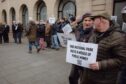 Protesters outside Perth and Kinross Council HQ, one holding a sign saying 'the national park is a waste of public money'