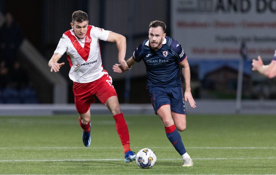 Raith Rovers defender Keith Watson has the ball at his feet as he holds off Airdrie defender Nikolay Todorov.