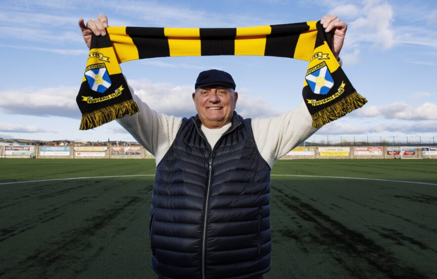 A grinning Dick Campbell holds aloft an East Fife scarf.