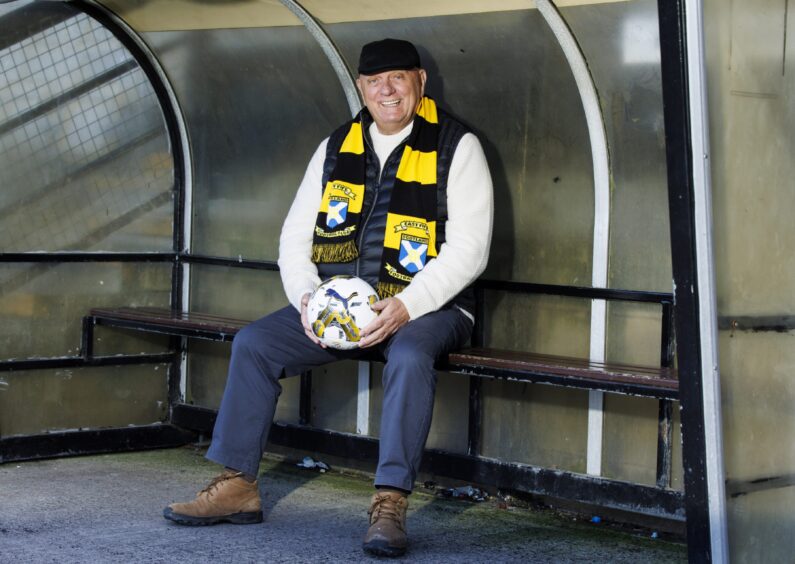 Dick Campbell wears an East Fife scarf and holds a ball as he sits in the dugout.