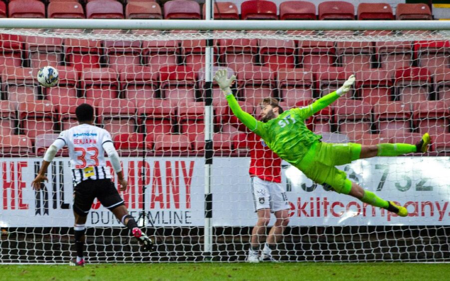 Dunfermline Athletic F.C. goalkeeper Deniz Mehmet dives acrobatically but cannot stop the ball from going into his net.