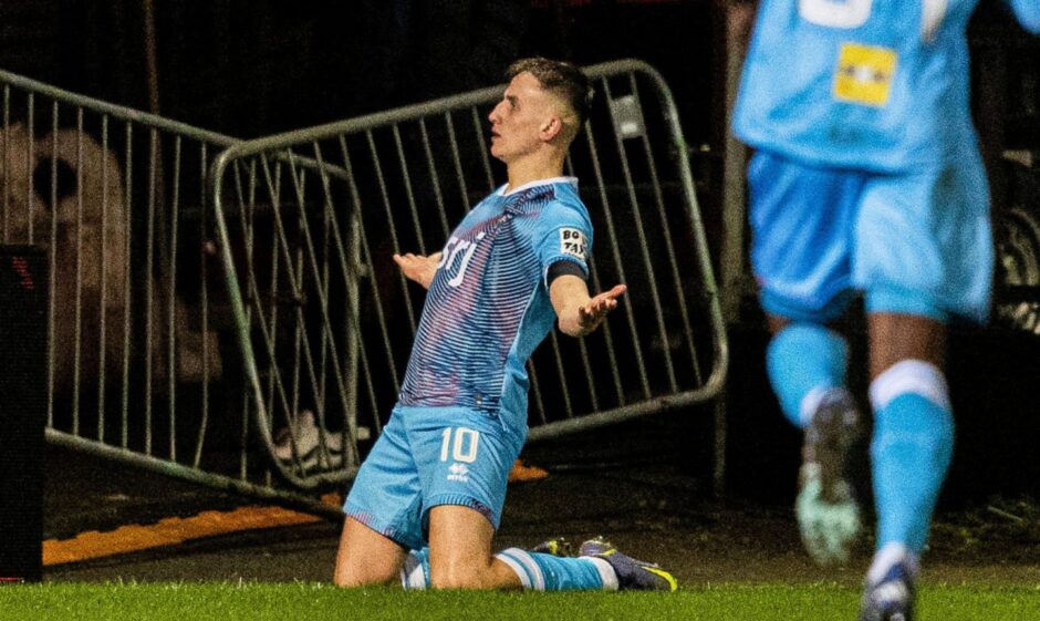 Matty Todd celebrates scoring DAFC's second goal against Partick Thistle as he slides on his knees with his arms outstretched.