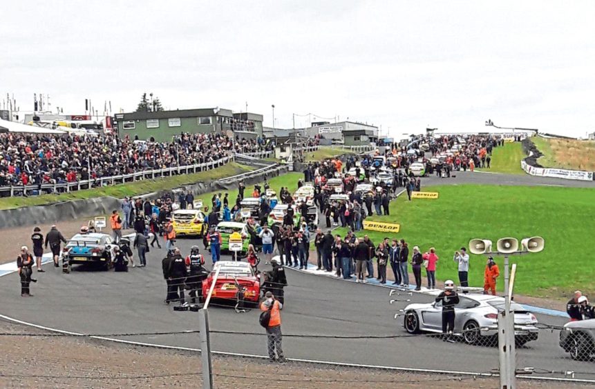 Image shows cars and crowds gathered for a mass start at Knockhill Racing Circuit.