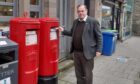 John Duff standing next to red post box outside Aberfeldy post office
