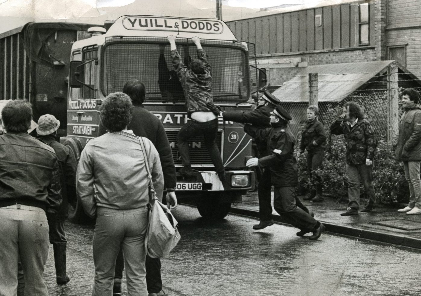 Pickets at Cartmore site in Dunfermline during the miners' strike in June 1984, with one man clinging to the front of a coal lorry 