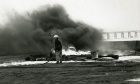 A firefighter at Dundee Airport in 1989, with smoke billowing behind him.