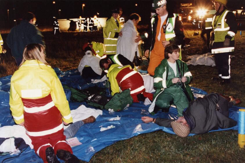 Paramedics and police officers get involved in 1994, with wounded laid out on a tarpaulin