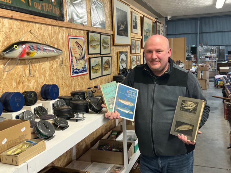 Auctioneer Gordon Delaney holding fishing items
