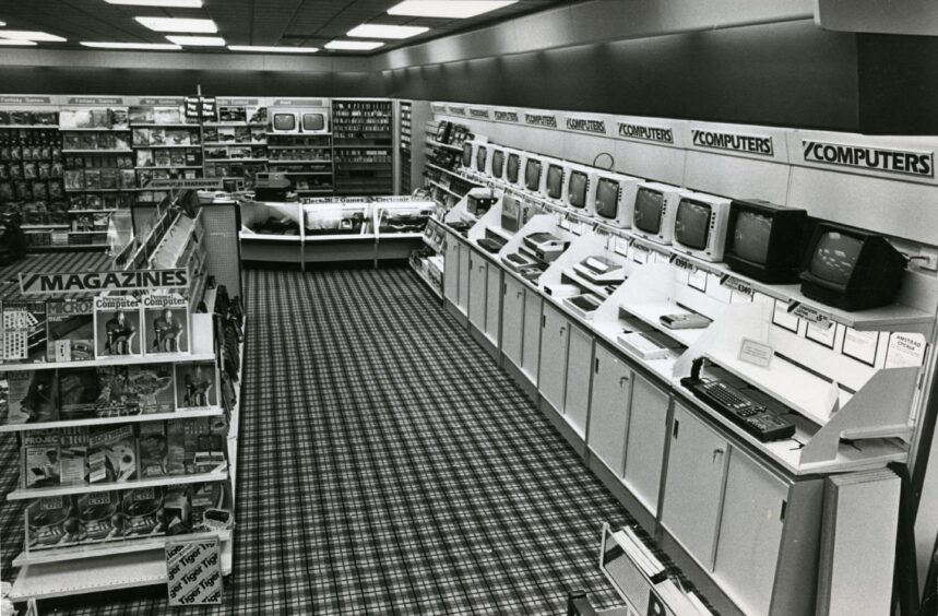 A row of computers against the wall next to books on the same subject.