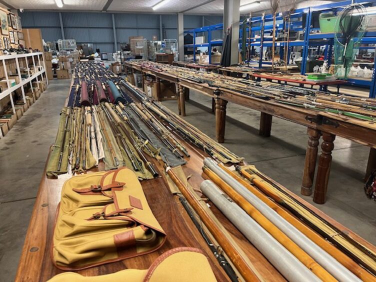 Table covered in fishing rods inside auction warehouse